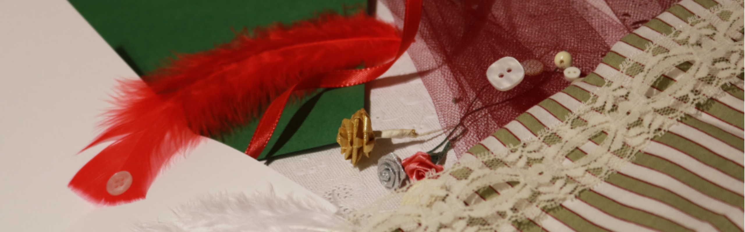Crafting materials, red feather, buttons, paper roses, lace, ribbons and tissue colorful paper